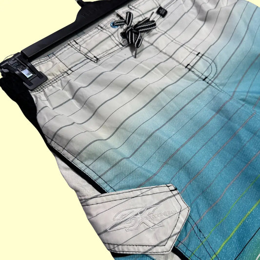 ZeroXposur ®striped board shorts in a stylish gradient of white, aqua blue, green, and black with fine line detailing.