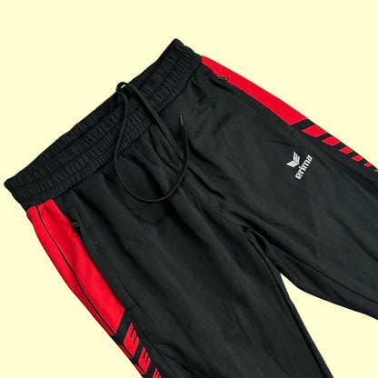 Erima Black Track Pants with striking red side panels and branding.